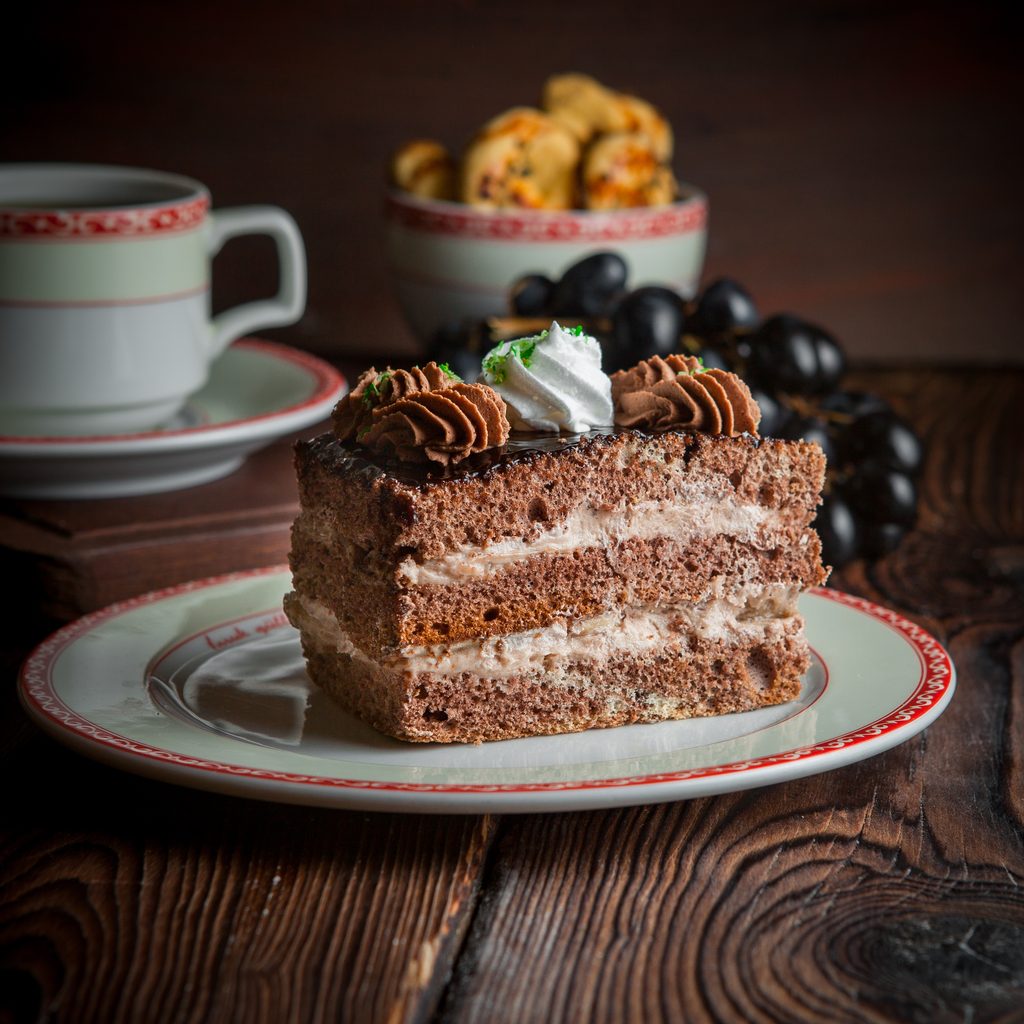 close up homemade cake with cup of tea, cookies and berries on wooden table